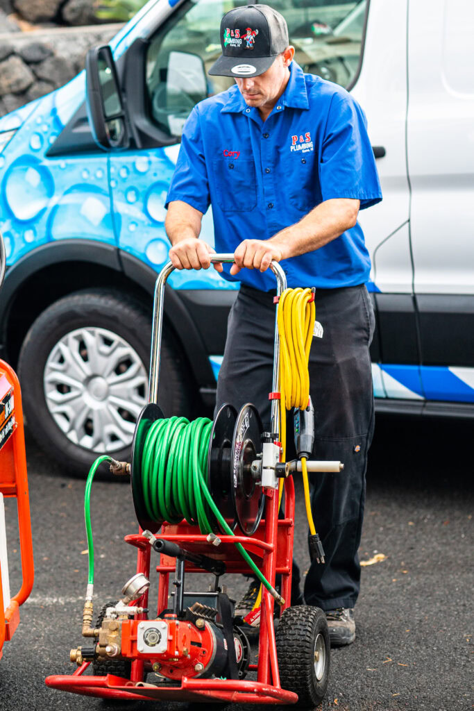 Plumber operating hydro jetting equipment for pipe cleaning in Hawaii.