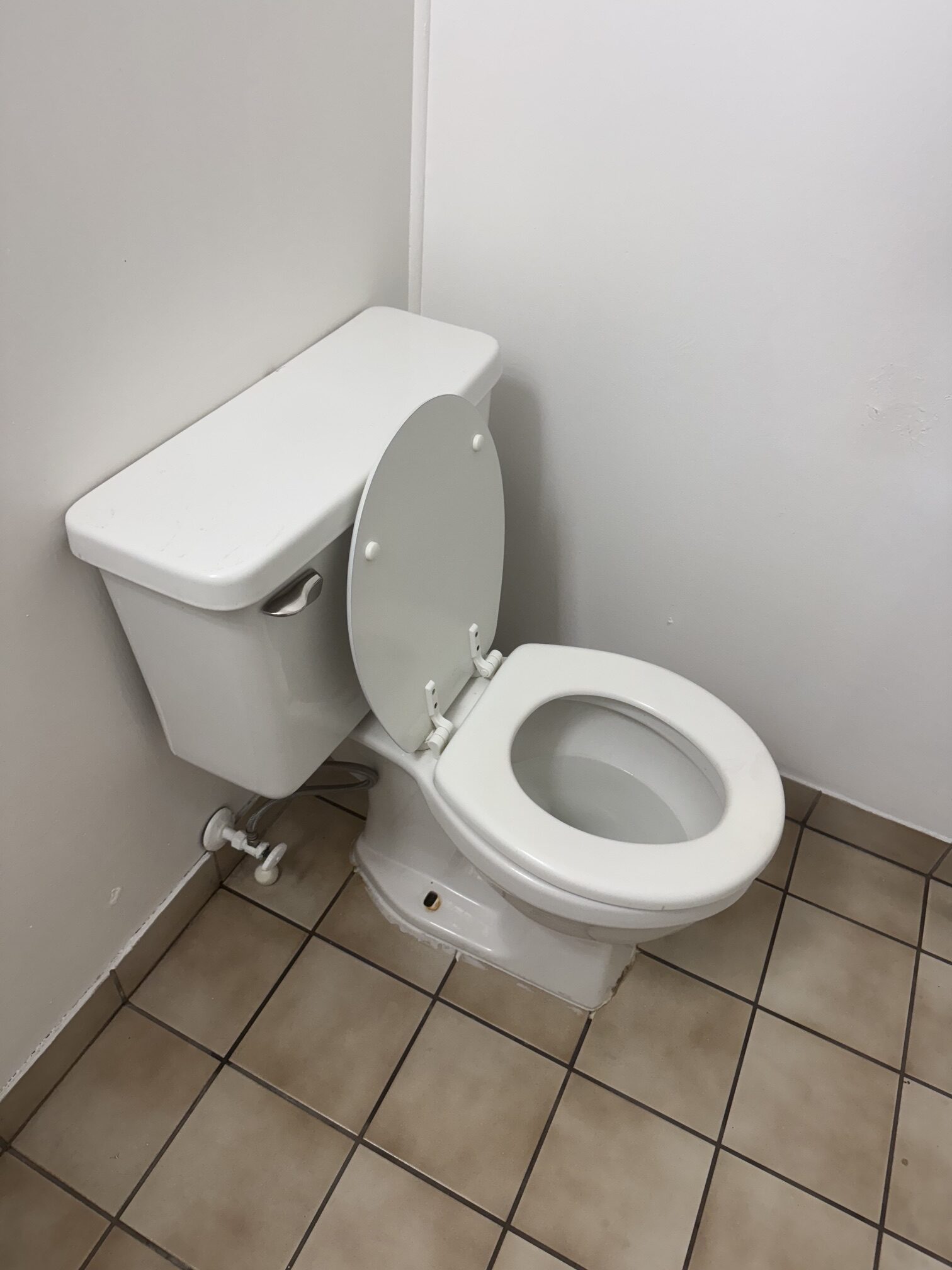 Clean white toilet in a bathroom with beige tile floor.
