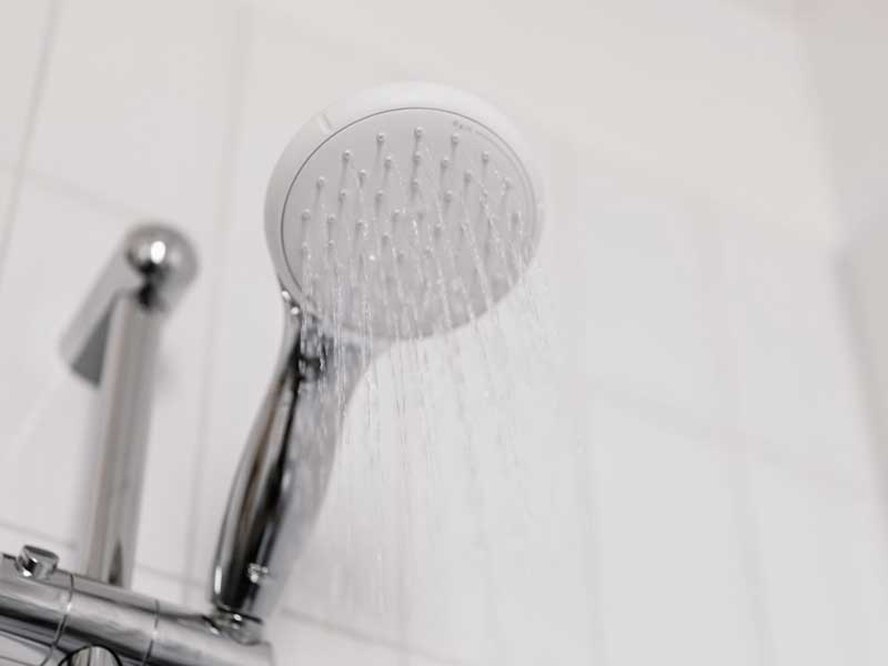 Showerhead with water spray in a modern bathroom setting.